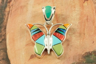 Stunning Butterfly Pendant featuring Genuine Sleeping Beauty Turquoise, Nevada Turquoise, Spiny Oyster Shell and Black Jade inlaid in Sterling Silver. Beautiful Fire and Ice Lab Opal Accents. Free 18" Sterling Silver Chain with Purchase of Pendant. Designed by Navajo Artist Calvin Begay. Signed by the artist.